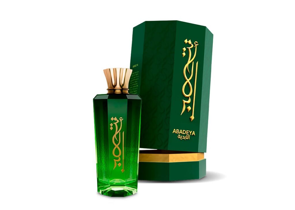 Perfume Abadeya em frasco verde esmeralda com tampa dourada ao lado de caixa verde com inscrições douradas.