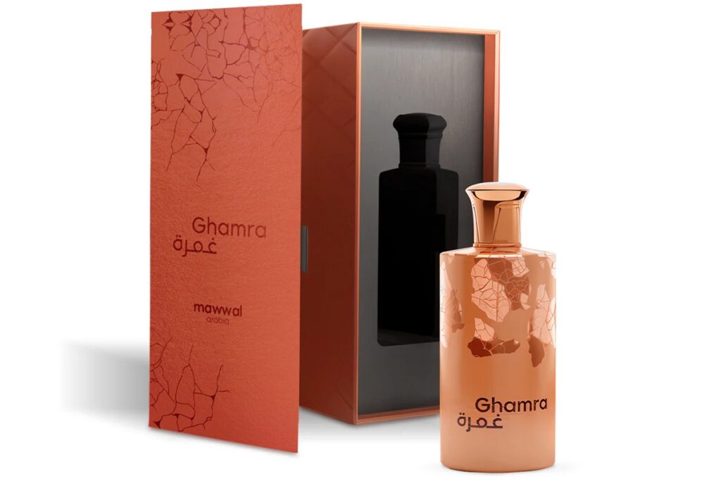 Frasco cobre metálico do perfume Ghamra Mawwal Arabic ao lado de caixa elegante em tom terracota com textura e detalhes craquelados