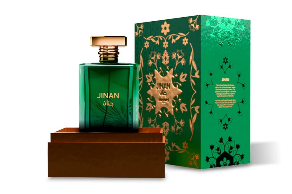 Frasco verde com tampa dourada do perfume Jinan Mawwal Arabic ao lado de caixa verde com detalhes florais dourados