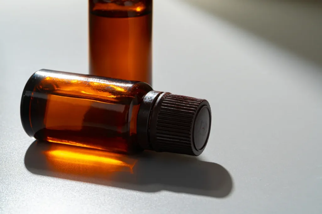 frasco de vidro âmbar deitado sobre uma superfície clara com outro frasco ao fundo