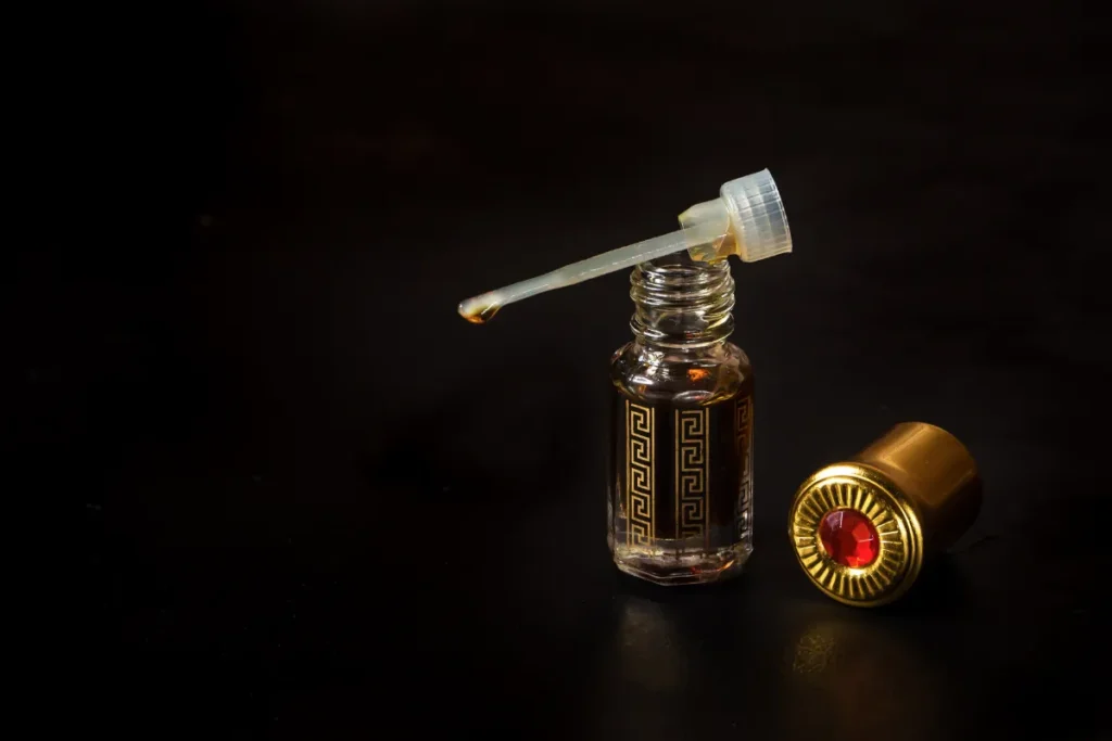 pequeno frasco de perfume com conta-gotas aberto sobre fundo escuro