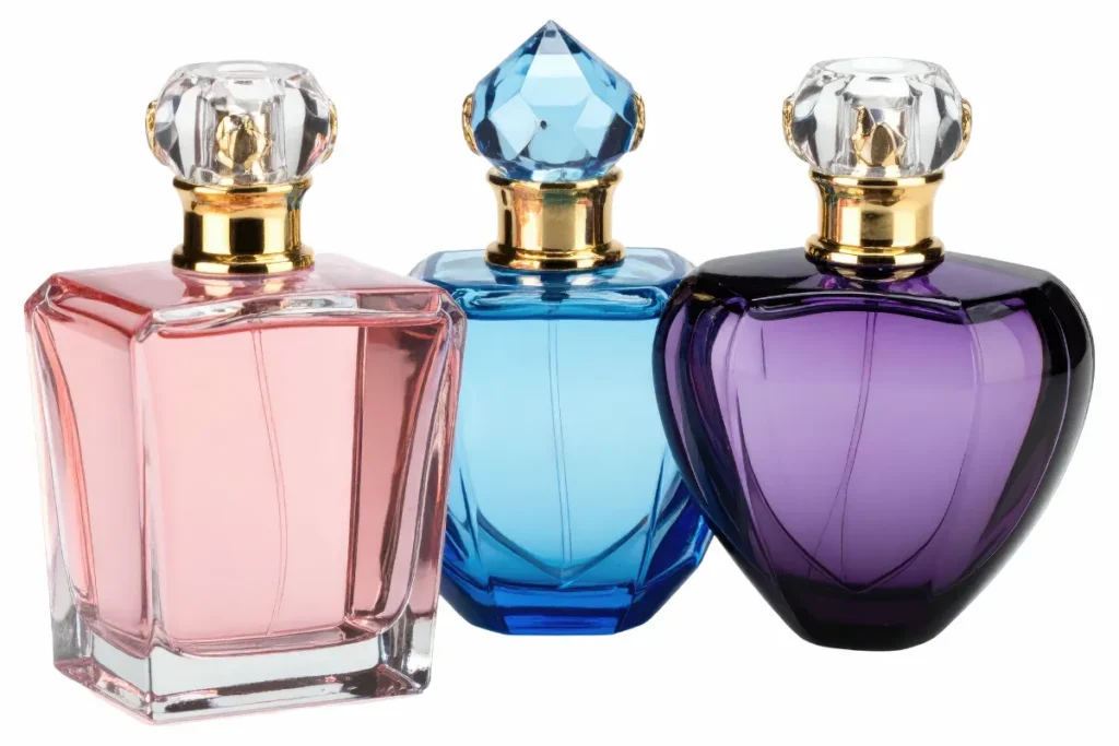três frascos de perfume coloridos nas cores rosa azul e roxo com tampa dourada