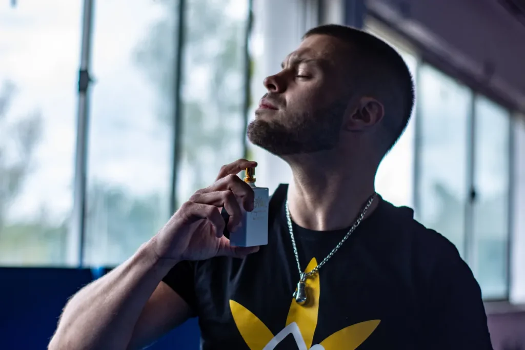 homem aplicando perfume na região do pescoço com um frasco pequeno na mão