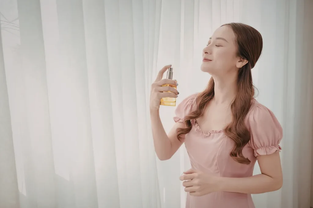 Mulher com olhos fechados sentindo o aroma de perfume que acabou de aplicar