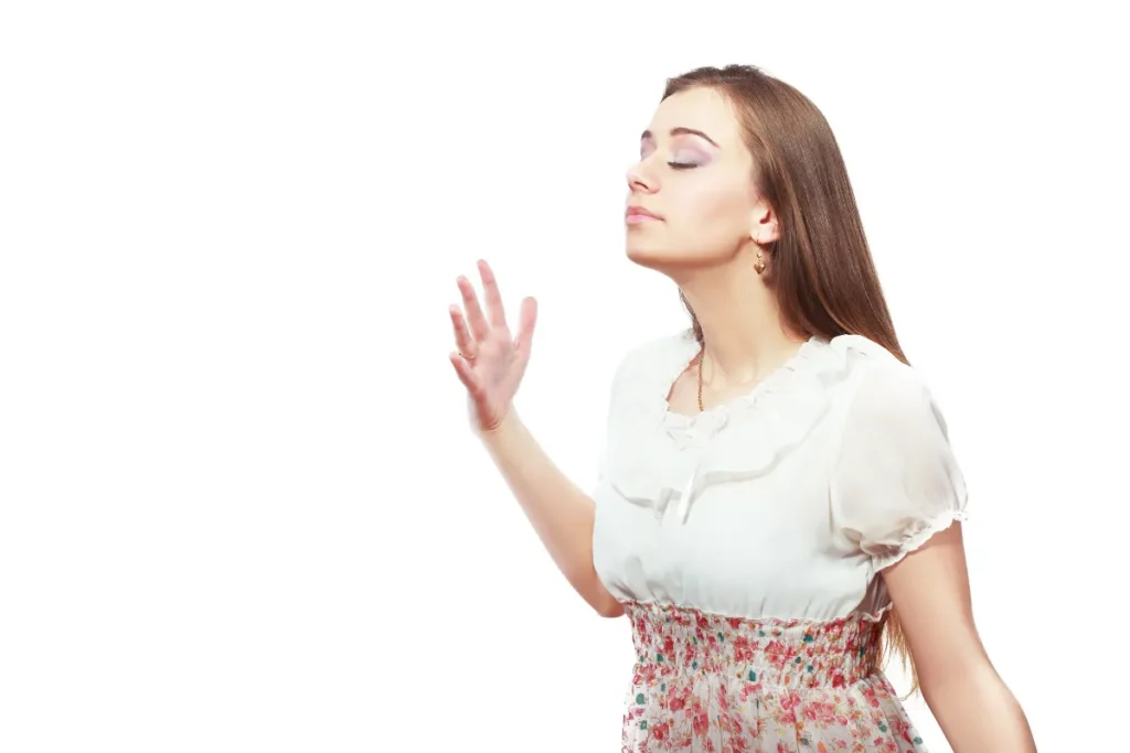 Mulher com olhos fechados percebendo cheiro no ar após aplicar perfume