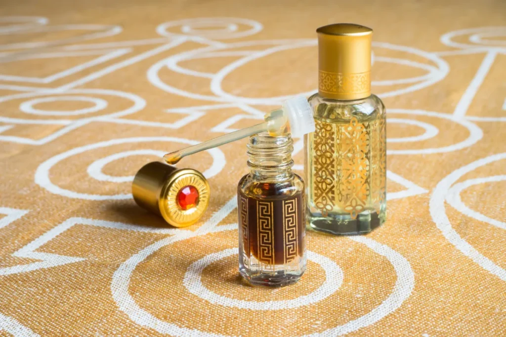 dois pequenos frascos de perfume com detalhes decorativos e aplicador aberto sobre superfície estampada
