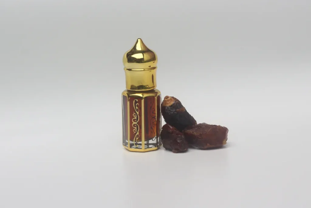 pequeno frasco dourado de óleo de perfume ao lado de resinas aromáticas