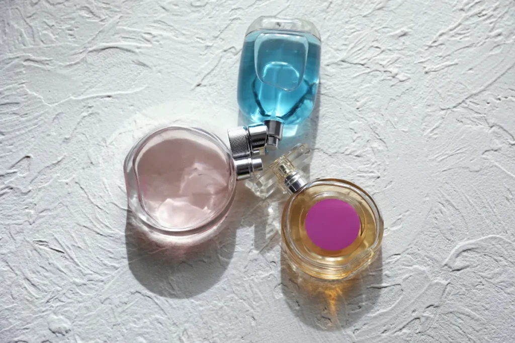 frascos de perfume com líquidos coloridos sobre superfície branca texturizada