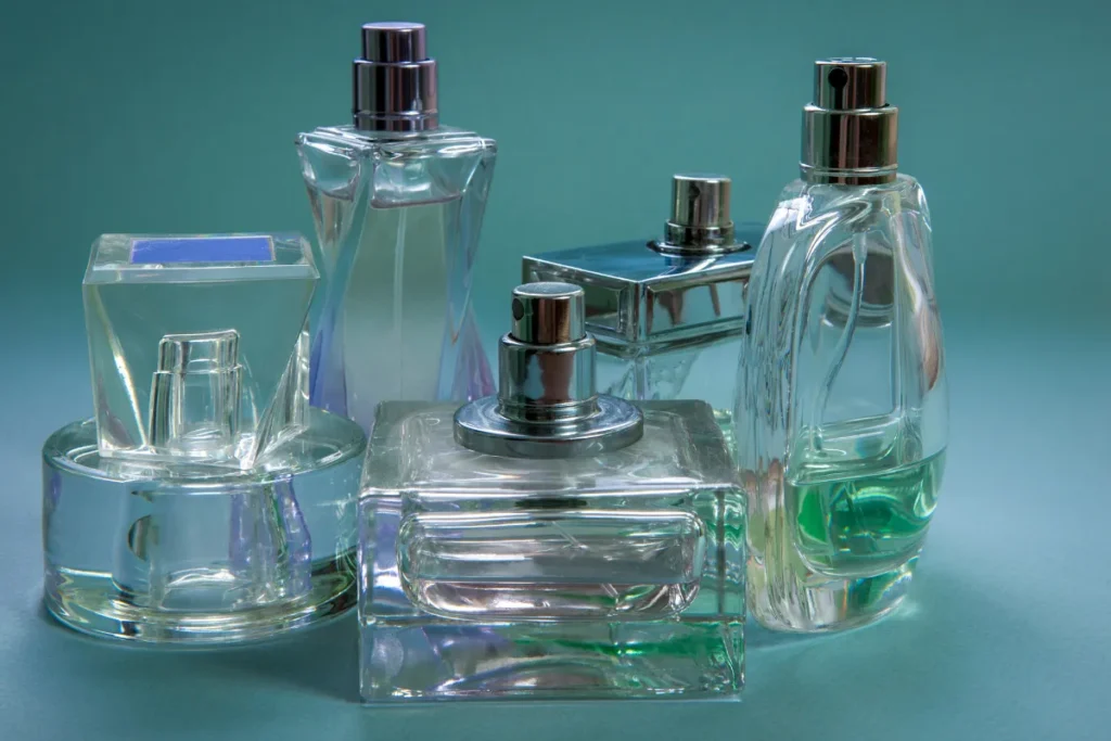 frascos de perfume de vidro transparente com líquido em diferentes tons sobre fundo azul
