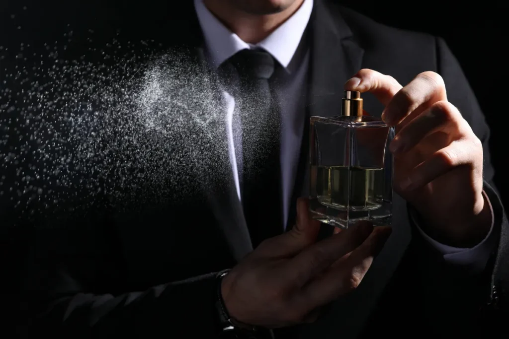 Homem segurando frasco de perfume enquanto borrifa a fragrância no ar