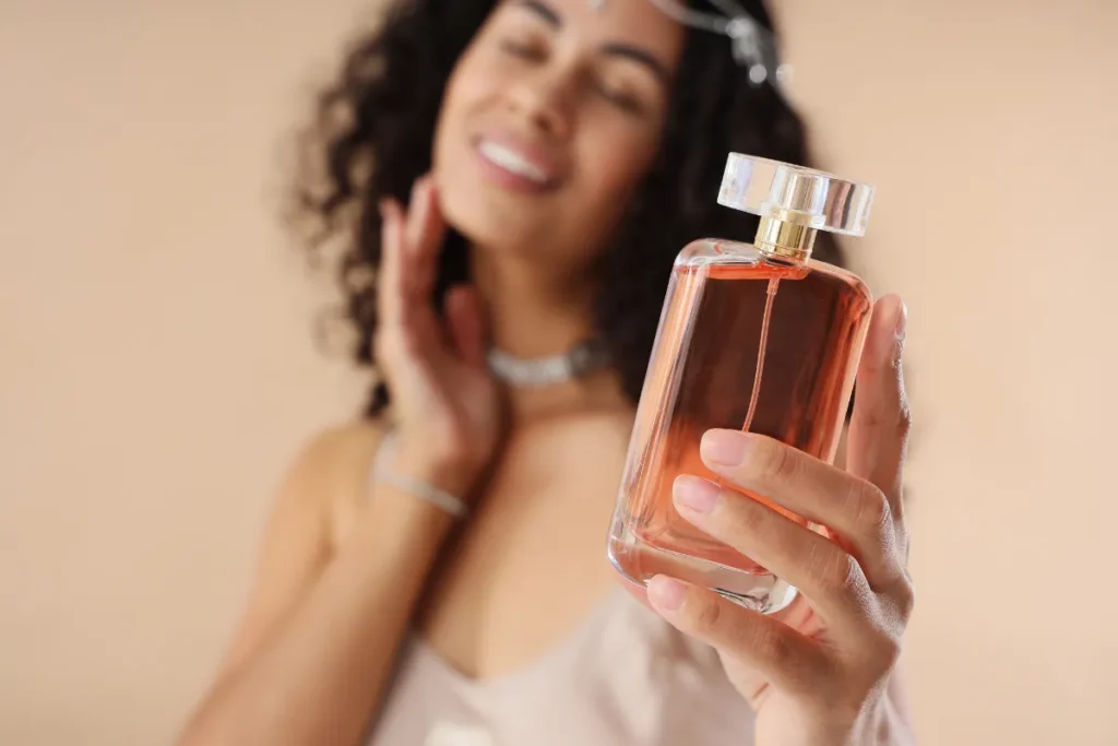 Mulher segurando frasco de perfume moderno próximo ao rosto