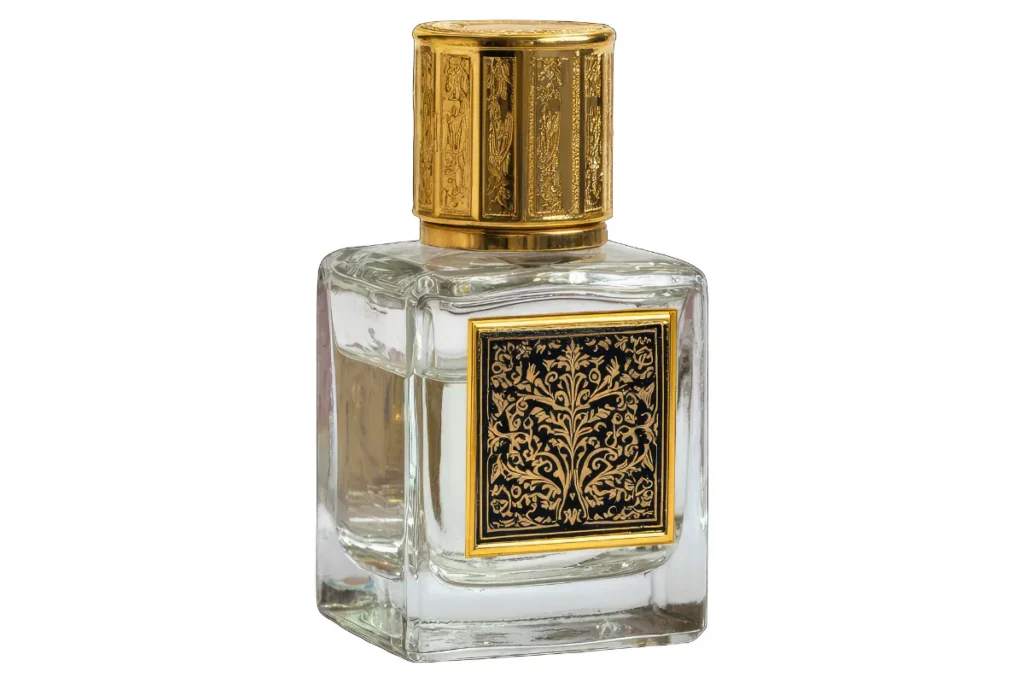 Frasco de perfume em vidro transparente com tampa dourada ornamentada e rótulo decorativo de estilo oriental.