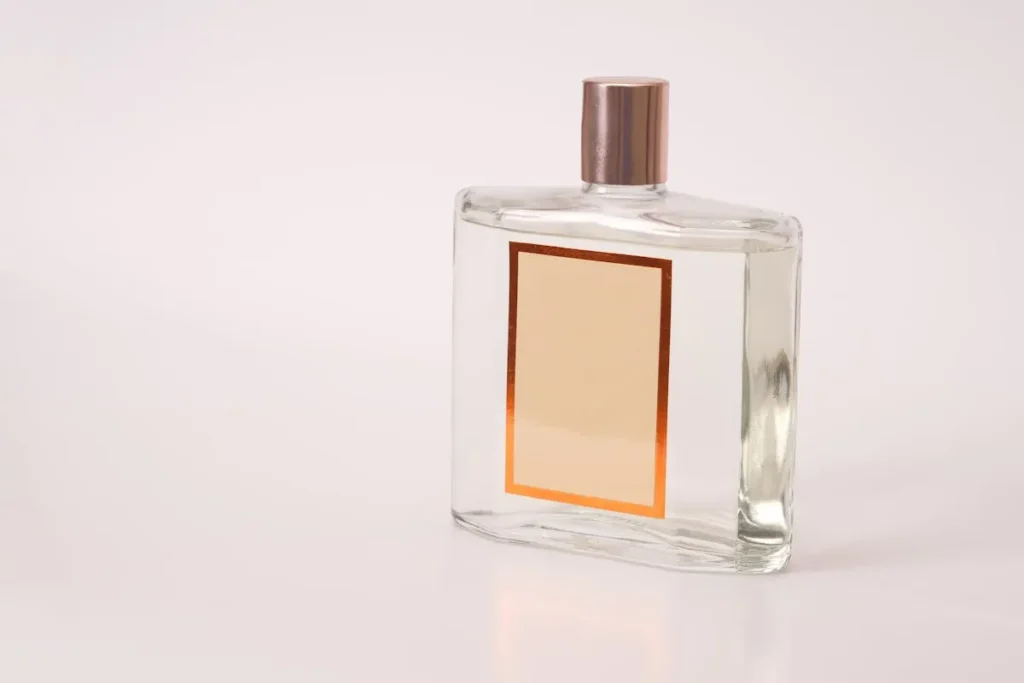 frasco de perfume masculino com design minimalista transparente e tampa metálica sobre fundo neutro