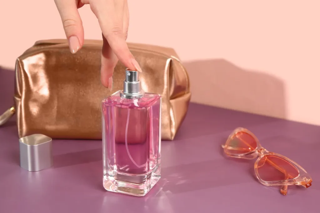 frasco de perfume sobre mesa com nécessaire e óculos ao lado