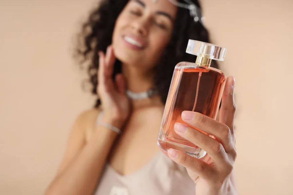 mulher segurando frasco de perfume com líquido rosado em destaque